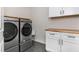 Well-organized laundry room with front loading washer and dryer, live edge wood counters and tile flooring at 3182 Windsor Lake Ne Dr, Atlanta, GA 30319