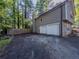 Attached two-car garage with driveway and fenced-in area on a home with neutral siding and stone accents at 5334 Post Road Pass, Stone Mountain, GA 30088