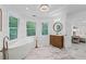 Bright bathroom with a modern tub, marble floors, wood vanity, and natural light at 605 Buttercup Trce, Johns Creek, GA 30022