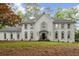 Elegant white home featuring symmetrical design, arched windows, and professionally landscaped front yard at 605 Buttercup Trce, Johns Creek, GA 30022