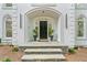 Elegant front entrance features a black door, stone steps, and decorative plants in urns at 605 Buttercup Trce, Johns Creek, GA 30022