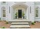 Inviting front entrance featuring stone steps, black door with transom window, and potted plants at 605 Buttercup Trce, Johns Creek, GA 30022