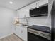 Well-lit kitchenette features white cabinets and stainless steel appliances at 605 Buttercup Trce, Johns Creek, GA 30022