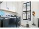 Convenient laundry room featuring modern appliances, stylish tile floors, and built-in cabinets at 201 Dobbs Rd, Woodstock, GA 30188
