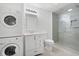 Well-lit bathroom featuring a glass shower, stacked washer and dryer, and classic white vanity at 5034 Kingsbridge Pass, Powder Springs, GA 30127