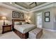 This main bedroom has a tray ceiling and upholstered bed at 8340 Royal Melbourne Way, Duluth, GA 30097