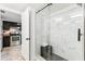 Modern bathroom featuring a glass-enclosed shower and neutral-toned tile. The kitchen is in the background at 199 14Th Ne St # 2312, Atlanta, GA 30309