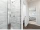 Modern bathroom featuring a glass shower with neutral tile and wood-look floors with a view to a bedroom at 3062 Cambridge Mill St, Acworth, GA 30102