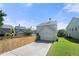View of the backyard showcasing a detached garage, wooden fence, concrete driveway and lush green grass at 3826 Baxley Village Trl, Suwanee, GA 30024