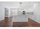 Open-concept kitchen with white cabinets, hardwood floors, an island, and a seamless transition to the mud room at 3826 Baxley Village Trl, Suwanee, GA 30024