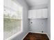 Well-lit laundry room with wood floors and upper white cabinets, perfect for your daily chores at 3826 Baxley Village Trl, Suwanee, GA 30024