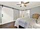Cozy bedroom featuring barn doors, wood floors, a ceiling fan, and neutral colors at 4353 White Oak Dr, Sugar Hill, GA 30518