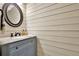 Stylish powder room with a granite-topped vanity, round mirror, and decorative wall paneling at 4353 White Oak Dr, Sugar Hill, GA 30518