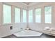 Bright bathroom showcasing a corner bathtub, tiled walls, and frosted windows for privacy at 2682 Boulder Creek Ne Dr, Roswell, GA 30075