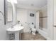 Charming bathroom with a white pedestal sink, decorative mirror, standard toilet, and shower-tub combo at 4101 Rickenbacker Ne Dr, Atlanta, GA 30342