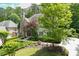 Home featuring a stone chimney, beautiful landscaping, lush trees and greenery, and circular driveway at 4101 Rickenbacker Ne Dr, Atlanta, GA 30342