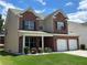 Attractive two-story brick home with a two-car garage, a manicured lawn, and a welcoming covered front porch at 1777 Weatherbrook Cir, Lawrenceville, GA 30043