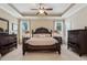 Primary bedroom featuring trey ceiling, dark wood furniture set and two side windows at 3365 Buffington Ln, Cumming, GA 30040