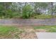 View of backyard featuring a retaining wall and a partially grassy area with young trees at 3399 Lake Frg, Fairburn, GA 30213