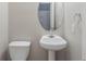 Pedestal sink and toilet in a neutral-toned bathroom with decorative round mirror at 3399 Lake Frg, Fairburn, GA 30213