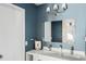 Bathroom featuring double sinks, a large mirror, modern vanity, and sleek blue walls at 4568 Oswood Ct, Tucker, GA 30084
