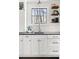Kitchen counter with white cabinets, stainless steel sink, floating shelves and charming tile backsplash at 4568 Oswood Ct, Tucker, GA 30084