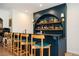Stylish home bar featuring open shelving, unique lighting, and seating for five at 5102 Chastleton Dr, Stone Mountain, GA 30087