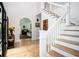 Bright foyer with a white staircase, hardwood floors, arched doorway, and decor at 5102 Chastleton Dr, Stone Mountain, GA 30087