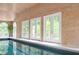 Indoor pool featuring light wood paneled walls, arched window, and glass doors to the outside at 5102 Chastleton Dr, Stone Mountain, GA 30087