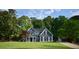 Beautiful two-story home with dark siding, white trim, mature trees and a large manicured front lawn at 219 Maple Creek, Woodstock, GA 30188