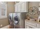 Well-equipped laundry room with stainless steel washer and dryer, storage cabinets, and a utility sink at 3341 Anna Ruby Ln, Buford, GA 30519