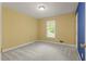 Sunny bedroom with neutral carpet, yellow walls, and a double-door closet at 670 Dena Dr, Canton, GA 30114