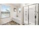 Bathroom featuring a bathtub, glass shower, and a window with neighborhood view at 1288 Hollingsworth Way, Dacula, GA 30019