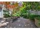 Serene courtyard featuring a red maple tree surrounded by brick pavers, stone walls, and well-maintained shrubbery at 2110 River Green Nw Dr # 2110, Atlanta, GA 30327