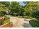 Wide concrete driveway lined with manicured bushes and brick walls, leading to a quiet street at 6825 Castleton Dr, Atlanta, GA 30328