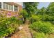 Brick pathway leads through lush gardens to a charming wooden gate with an arched entrance at 6825 Castleton Dr, Atlanta, GA 30328