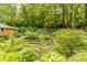 Tiered backyard gardens with walking path, mature trees, and colorful flowers at 6825 Castleton Dr, Atlanta, GA 30328