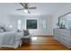 Bright primary bedroom with hardwood floors, a ceiling fan, and a gray dresser with mirror at 6825 Castleton Dr, Atlanta, GA 30328