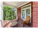 Covered porch featuring brick flooring, two wooden chairs, and a side table, perfect for outdoor relaxation at 3049 Brightwood Se Ln, Marietta, GA 30067