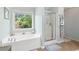 Corner soaking tub with a window view and separate glass-enclosed shower at 5415 Fieldfreen Dr, Cumming, GA 30028