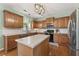 Well-lit kitchen with wooden cabinetry, stainless steel appliances, and island, complemented by warm hardwood floors at 5415 Fieldfreen Dr, Cumming, GA 30028