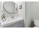 Clean powder room with a modern sink, a gray vanity, and a decorative round mirror for added elegance at 5415 Fieldfreen Dr, Cumming, GA 30028