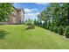 Beautiful backyard featuring tiered landscaping, mature trees, and lush green grass at 2430 Tack Hill Ct, Dacula, GA 30019