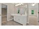 Bright bathroom featuring a large vanity, decorative mirror, access to bedroom and walk-in closet at 4910 Aldbury Ln, Suwanee, GA 30024
