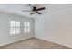 Bright bedroom features neutral carpeting, white walls and trim, a ceiling fan, and two windows with white shutters at 6006 Lanier Heights Cir, Buford, GA 30518