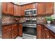 Kitchen showcasing stainless steel oven and microwave, tile backsplash, granite counters, and wood cabinetry at 4068 Cottage Oaks Dr, Acworth, GA 30101