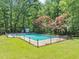 Fenced in swimming pool surrounded by mature trees and green lawn at 4820 Yeager Rd, Douglasville, GA 30135