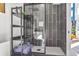 Modern bathroom with a glass enclosed shower featuring unique dark tiles, open shelving and white tile flooring at 3120 Godby Rd, Atlanta, GA 30349