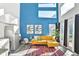 Bright living space with a blue accent wall, a mustard colored couch, and tall windows providing natural light at 3120 Godby Rd, Atlanta, GA 30349
