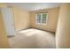 Bedroom with light-yellow walls featuring neutral carpet, a large window, and a double-door closet at 1411 Blackland Trl, Lawrenceville, GA 30043